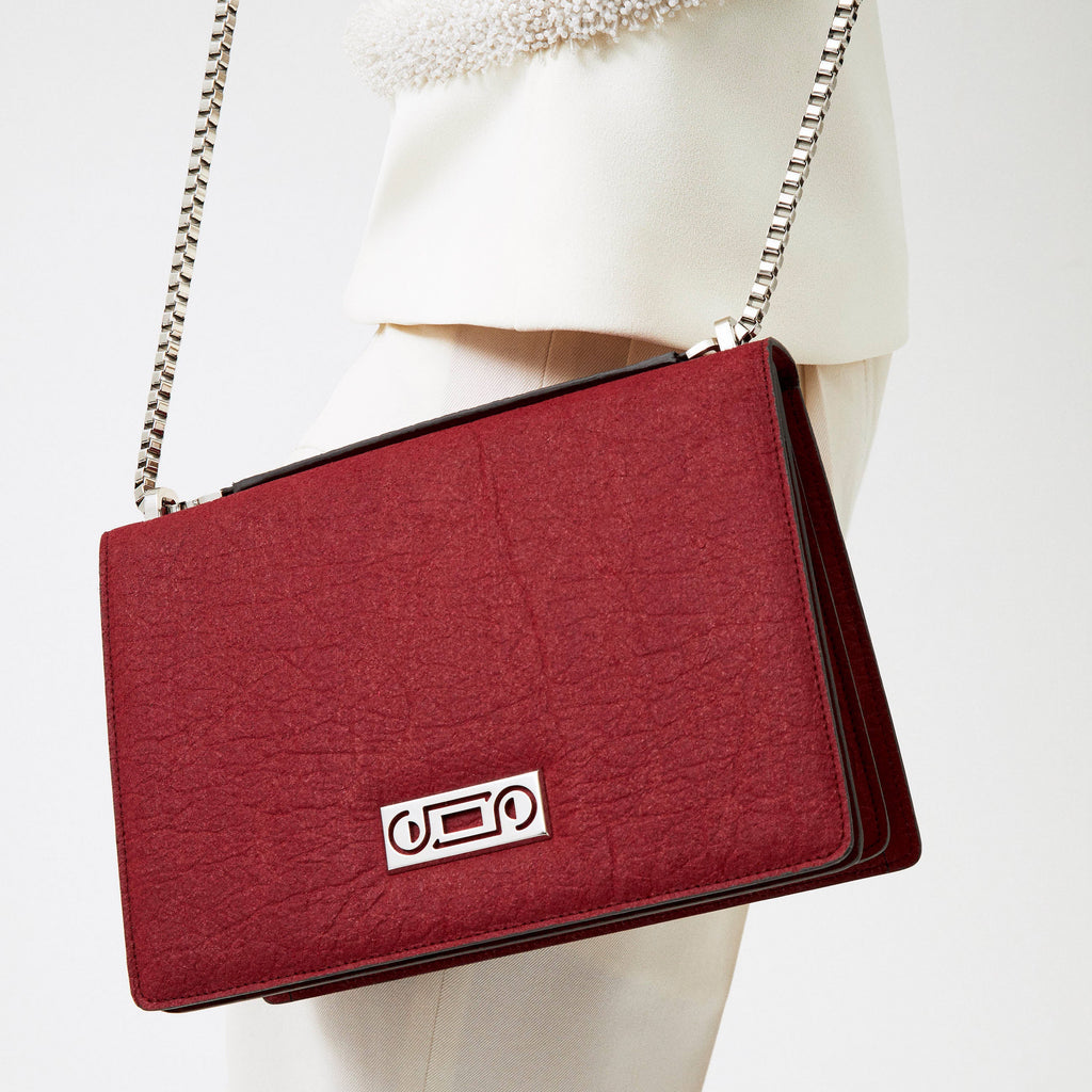 Editorial portrait of The Cristiana Vegan Shoulder Bag in red Piñatex, expressing sculptural minimalism, tactile materials, and refined contemporary elegance.
