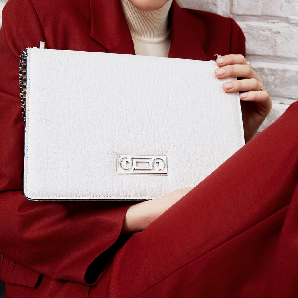 Editorial portrait of The Cristiana Vegan Shoulder Bag in white Piñatex expressing contemporary movement, sculptural elegance, and refined vegan craftsmanship.