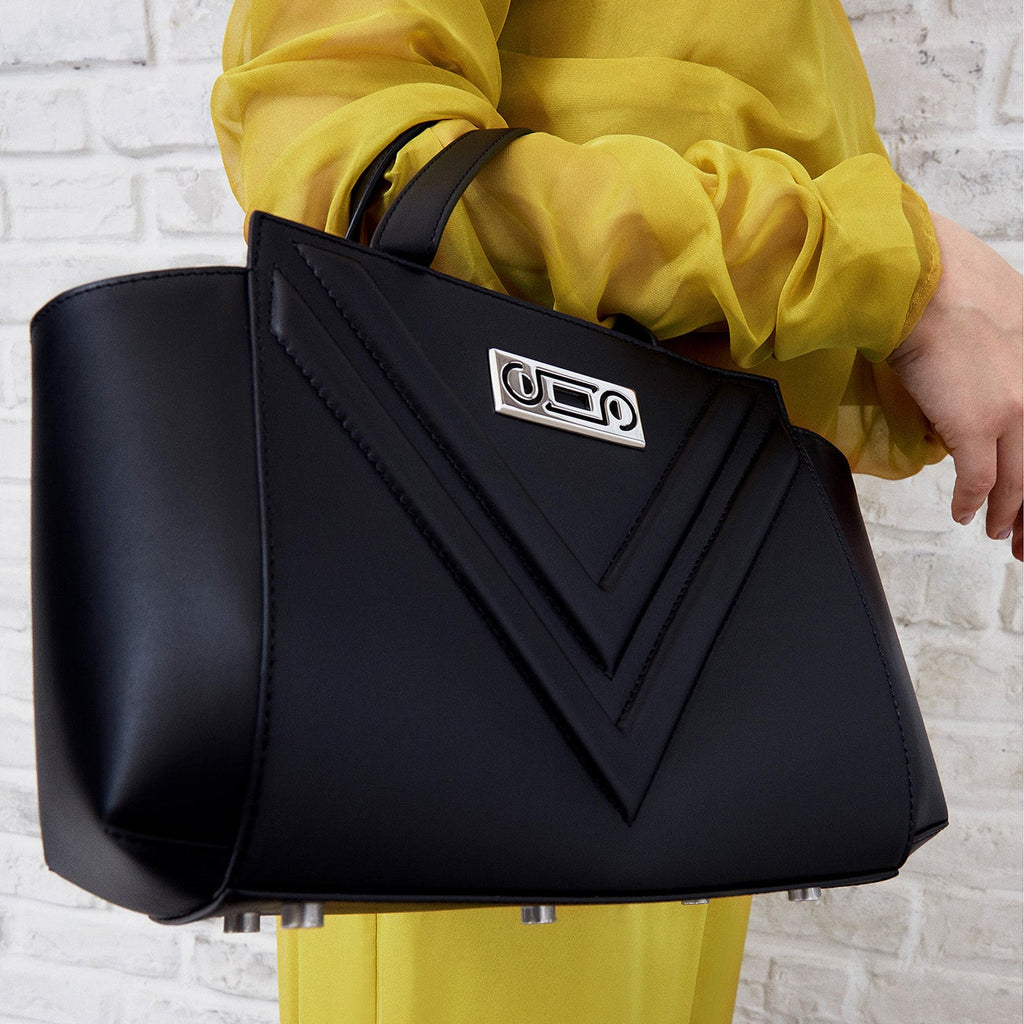 The Maja Little Tote Bag carried by a model in black leather, demonstrating versatile proportions and refined everyday elegance.