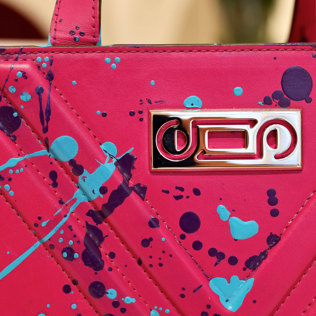 Close-up of The Maja Little “Stardust” featuring hand-painted leather, signature V-shaped construction, and refined metallic logo plaque detailing.