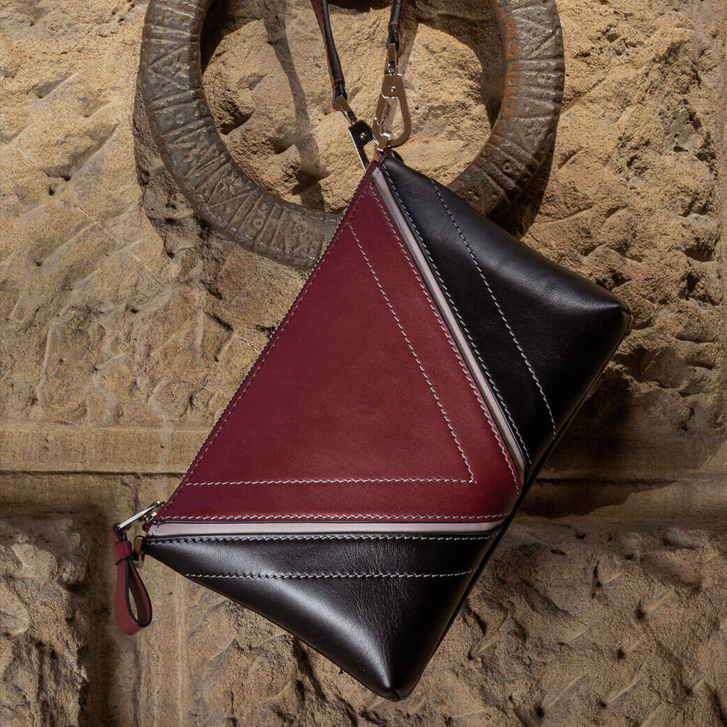 Editorial image of The Arianna Pouch with Studio Tondini’s signature V-shape construction creating a bordeaux leather triangle, expressing understated elegance and cosmopolitan sophistication.