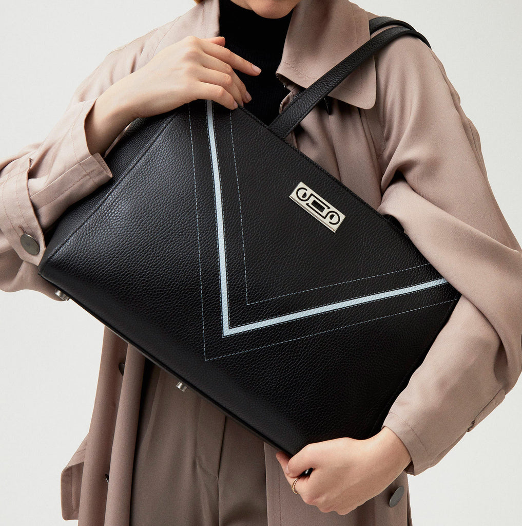 Model holding The Maja Monochrome Tote Bag in black pebbled leather, expressing understated elegance and contemporary sophistication.