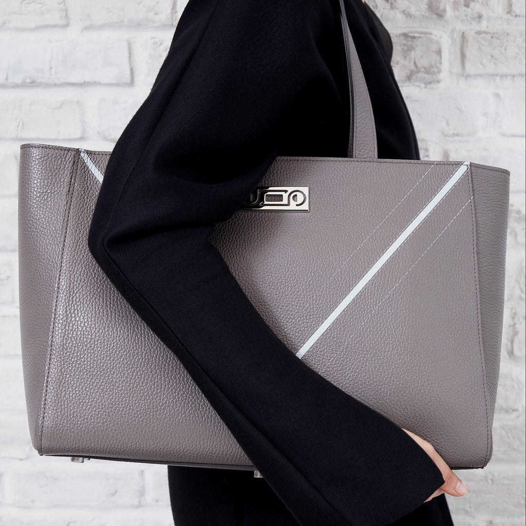 Model holding The Maja Monochrome Tote Bag in taupe pebbled leather, expressing understated elegance and contemporary sophistication.