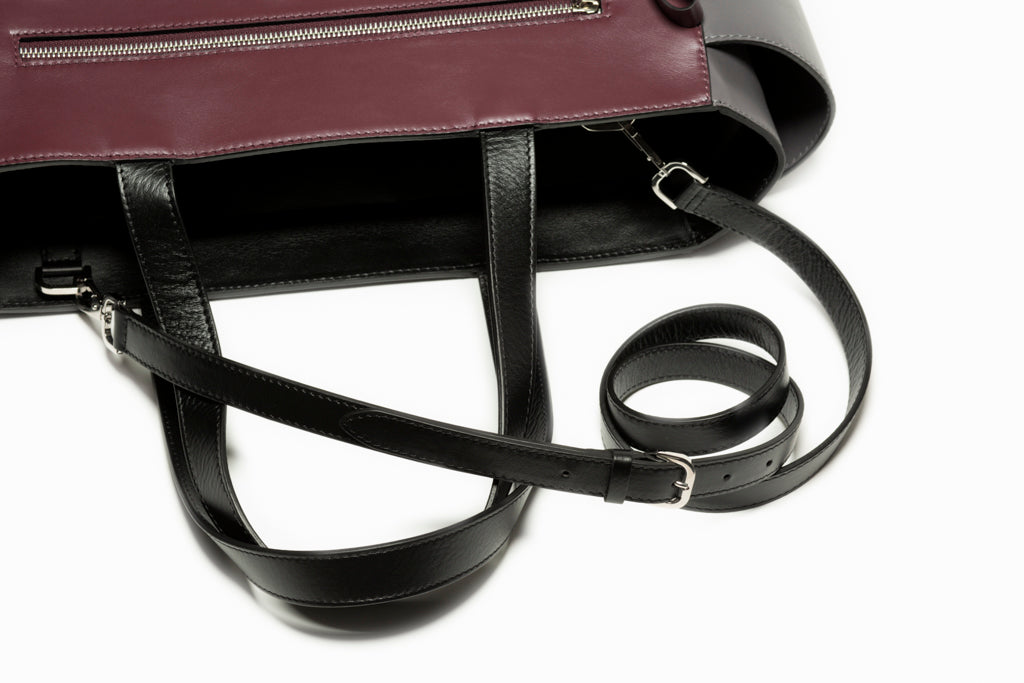 The Long Strap by Studio Tondini attached to The Maja Tote Bag. Black leather strap with visible buckle and metal hooks, enhancing refined versatility.