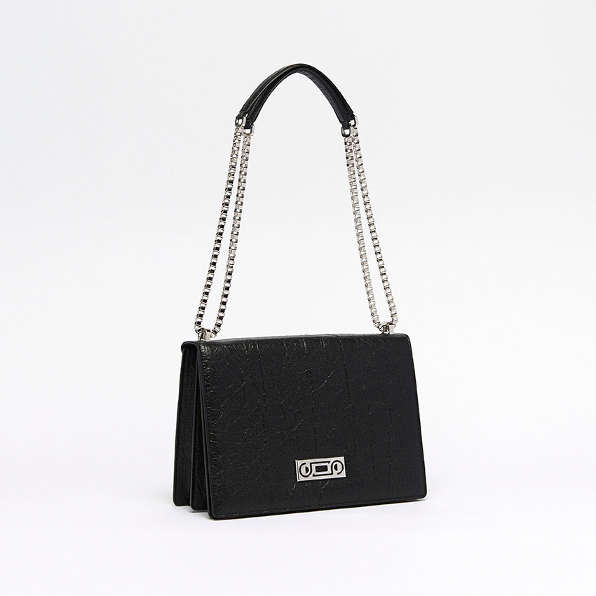 Three-quarter view of The Cristiana Vegan Shoulder Bag in black Piñatex highlighting composed proportions and refined chain detailing.