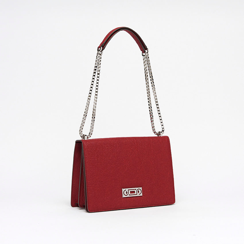Three-quarter view of The Cristiana Vegan Shoulder Bag in red Piñatex with refined structure and elegant chain strap detailing.