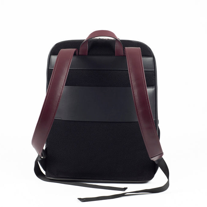 Back view of The Simona Backpack in smooth black leather with ergonomic shoulder straps in bordeaux leather and clean architectural construction.