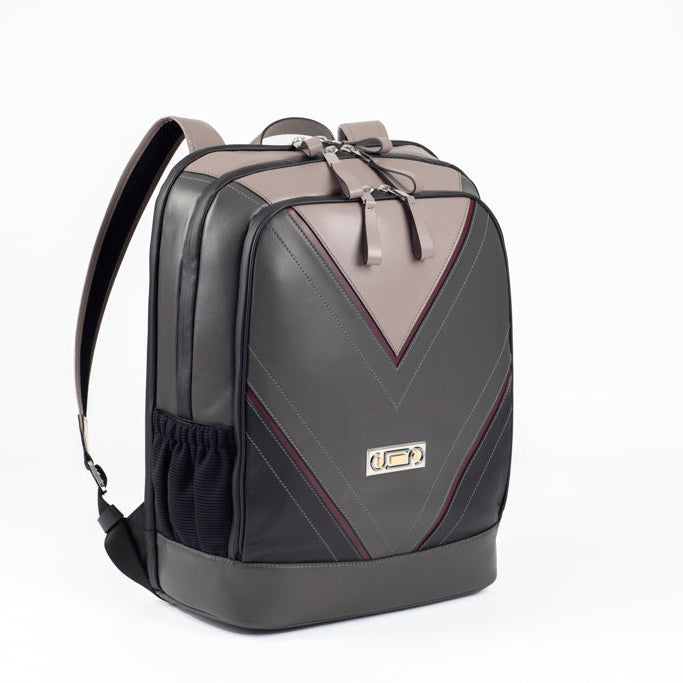 Three-quarter view of The Simona Backpack with Studio Tondini’s signature V-shape construction creating a light grey leather triangle, showcasing architectural contemporary craftsmanship.